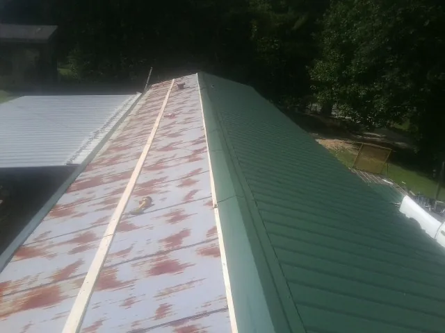 Old rusted panels beside newly installed green metal roofing — Wind Damage Roof Repair by Roofing Brothers in Airville