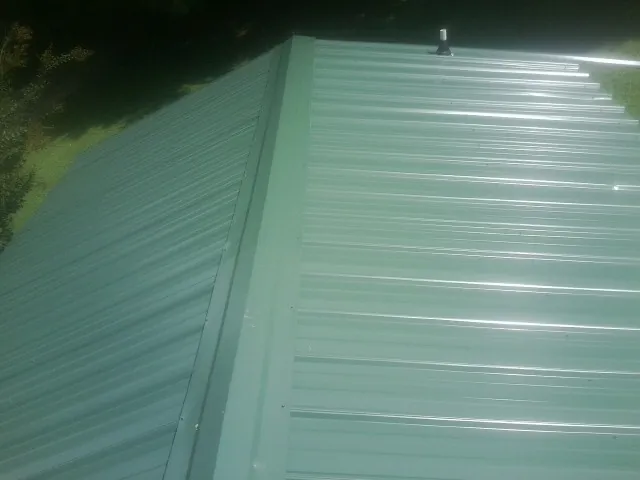 New green metal panels meeting at the ridge of a roof — Flat Roof Repair work by our crew in Airville