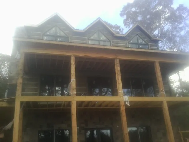 Dormers and porch framing on a large log home under construction — Roof Coating work by our crew in Airville