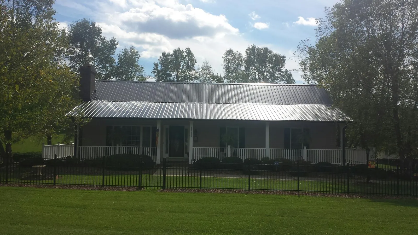 Gray metal roof on a brick ranch with a full width front porch — Gutter Guard Installation work by our crew in Airville