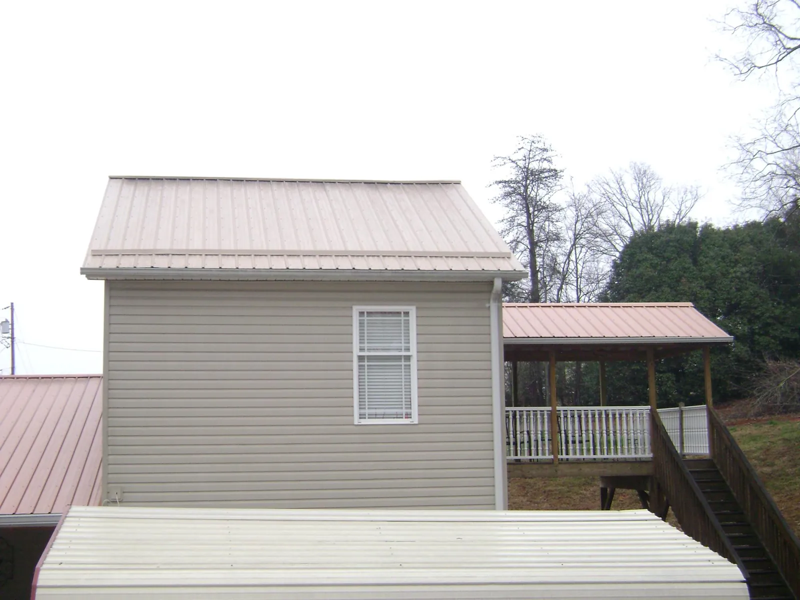 Tan metal roofs on a two story addition and attached porch, from a Roof Replacement job in Airville