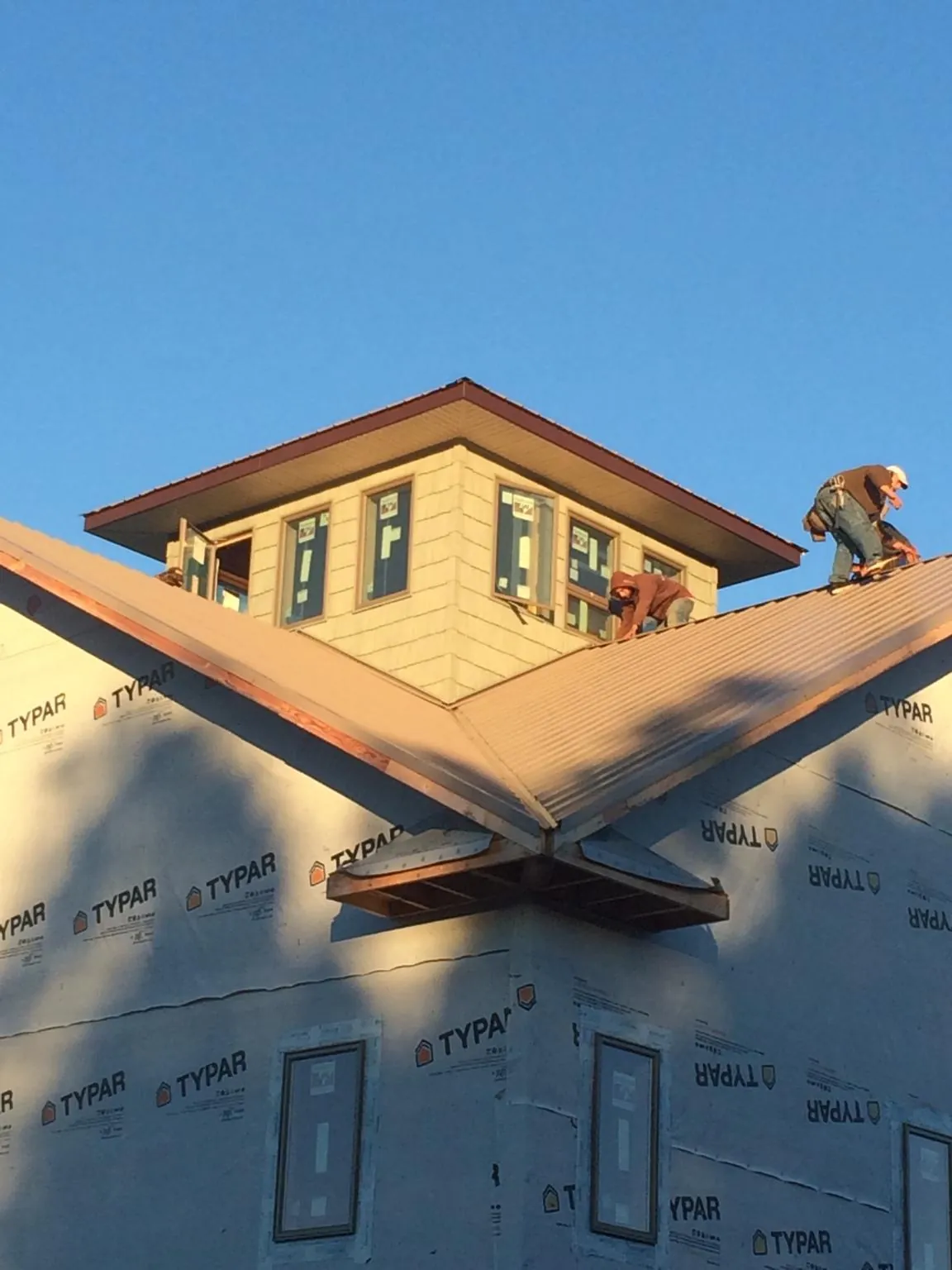 Roofers working around a rooftop cupola on a new metal roof at sunset — Roof Waterproofing in Airville by Roofing Brothers